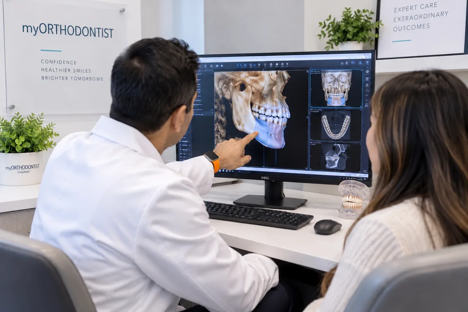 Orthodontist in a white clinical coat reviewing a 3D CBCT jaw reconstruction with a patient at myORTHODONTIST Coquitlam